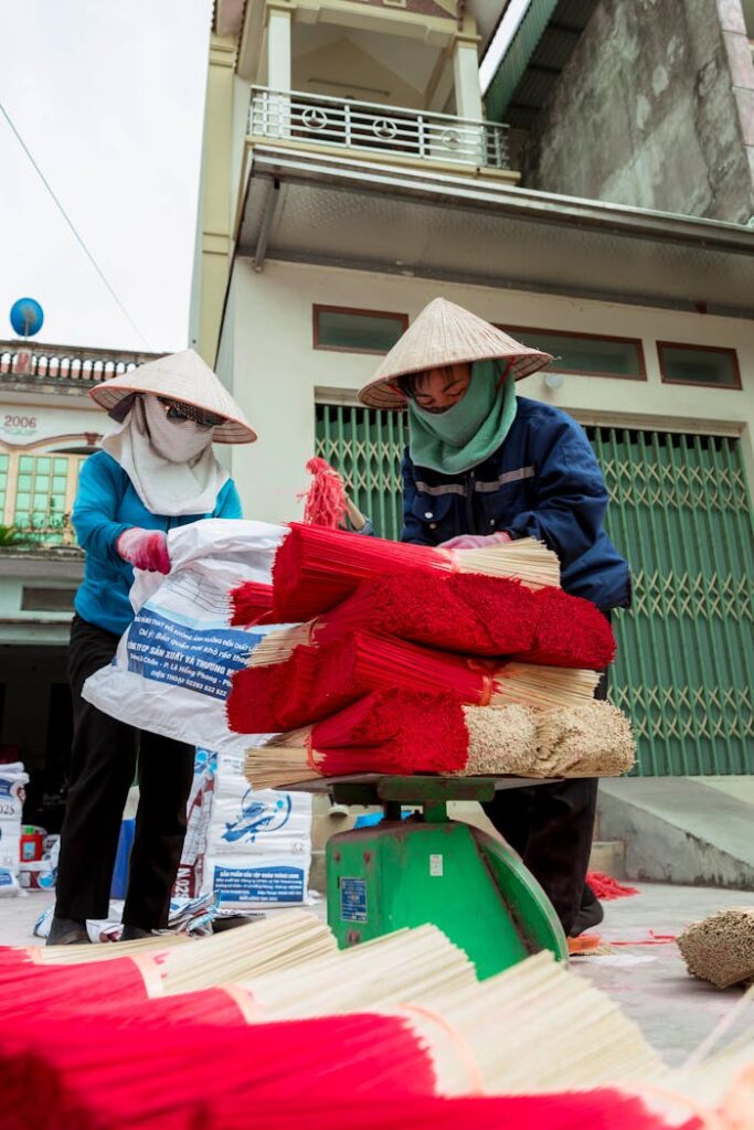 Two women in vietnamese hats are selling red and white straw